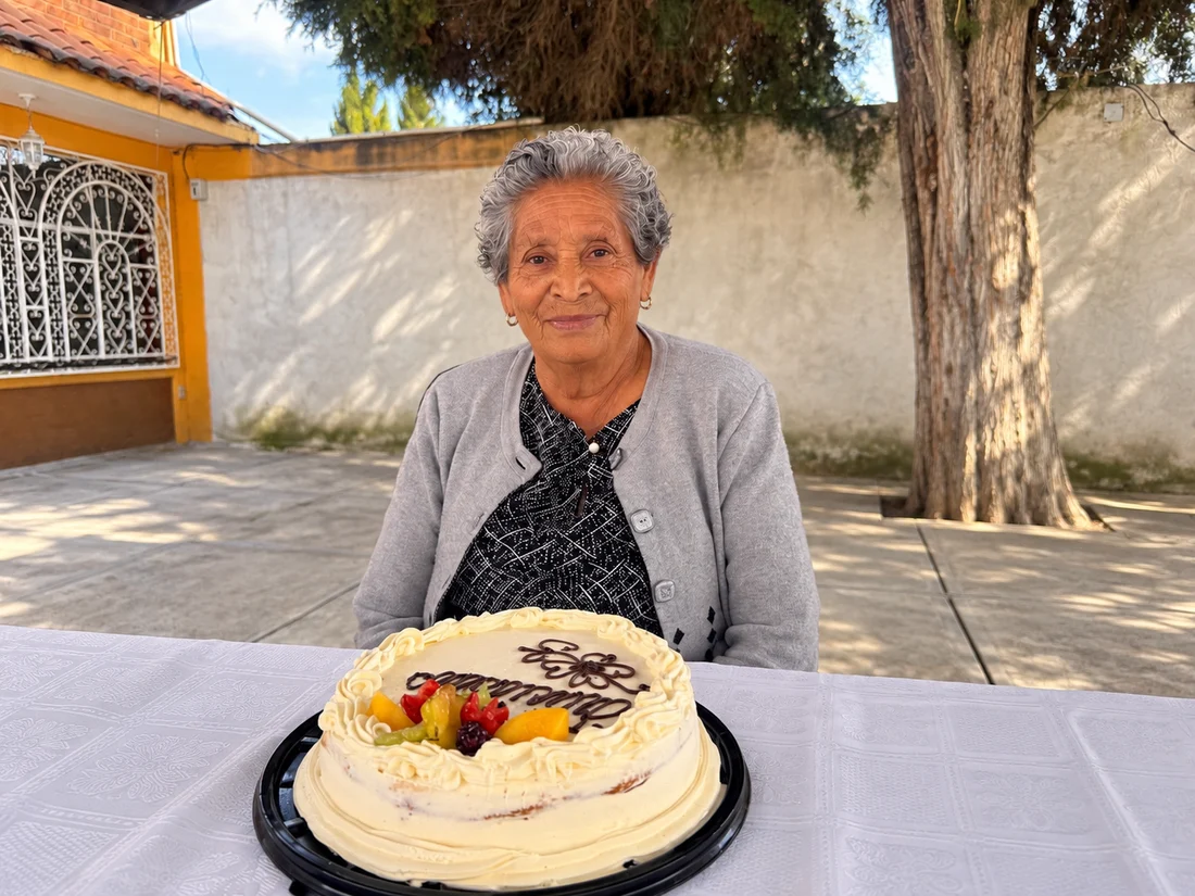 Vicenta sentada frente a un pastel blanco
